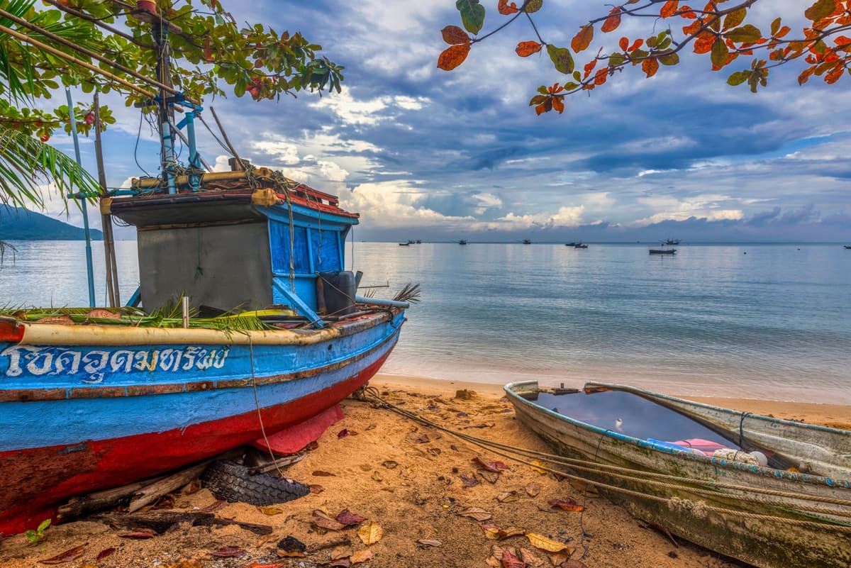 A painted fishing boat pulled up on the sand by the Andaman Sea