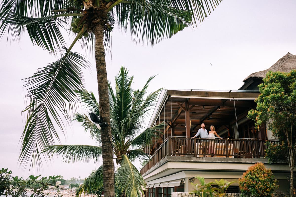 Travellers on a wooden balcony among palm trees