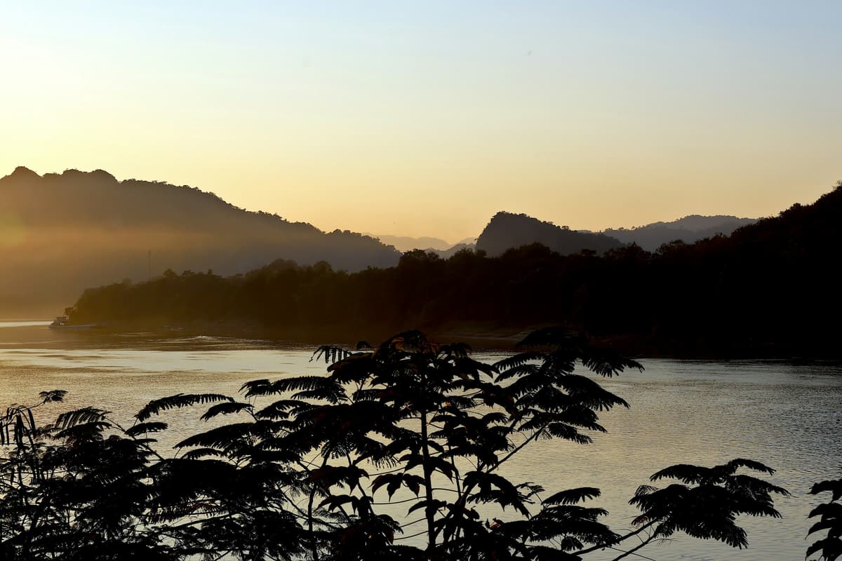 El Mekong en Luang Prabang a la puesta de sol, con las colinas envueltas en bruma en la otra orilla