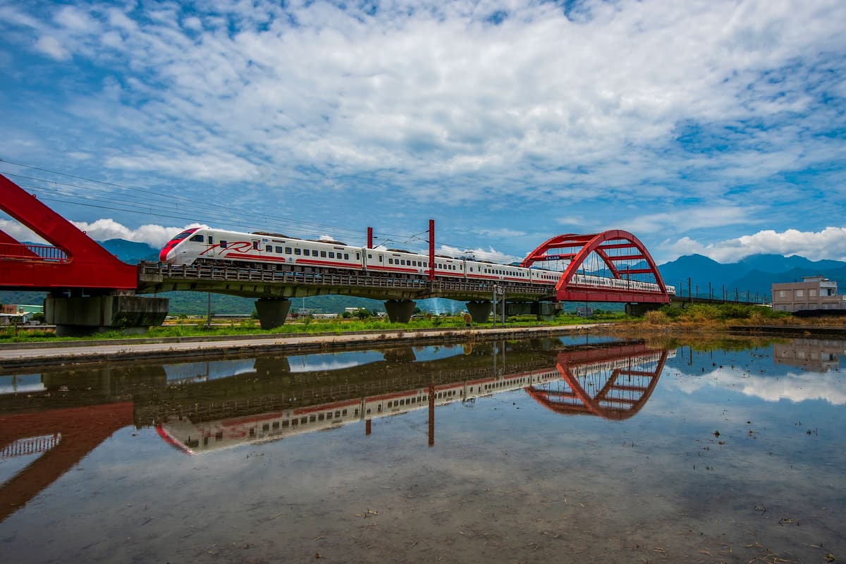 Un treno espresso attraversa un ponte rosso in mezzo alle risaie, sulla costa est di Taiwan