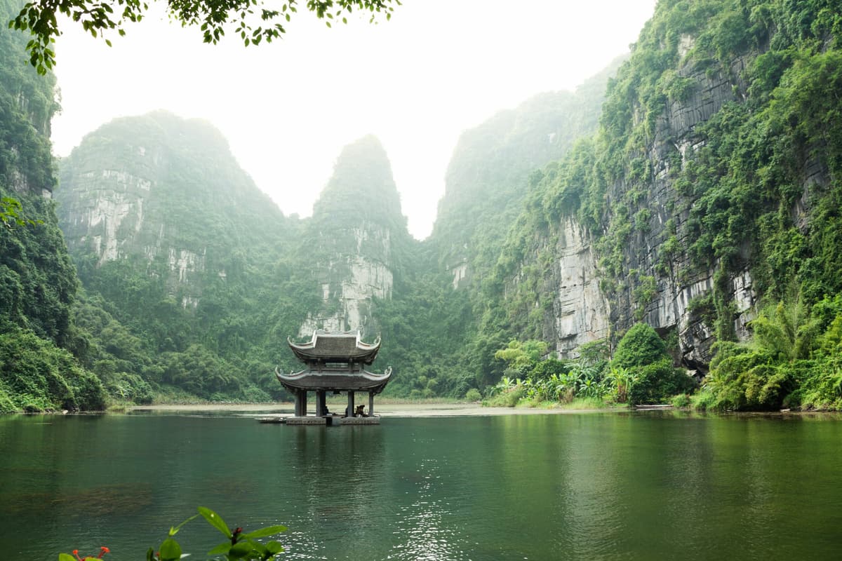 A pagoda on the water below karst cliffs at Trang An, Ninh Binh