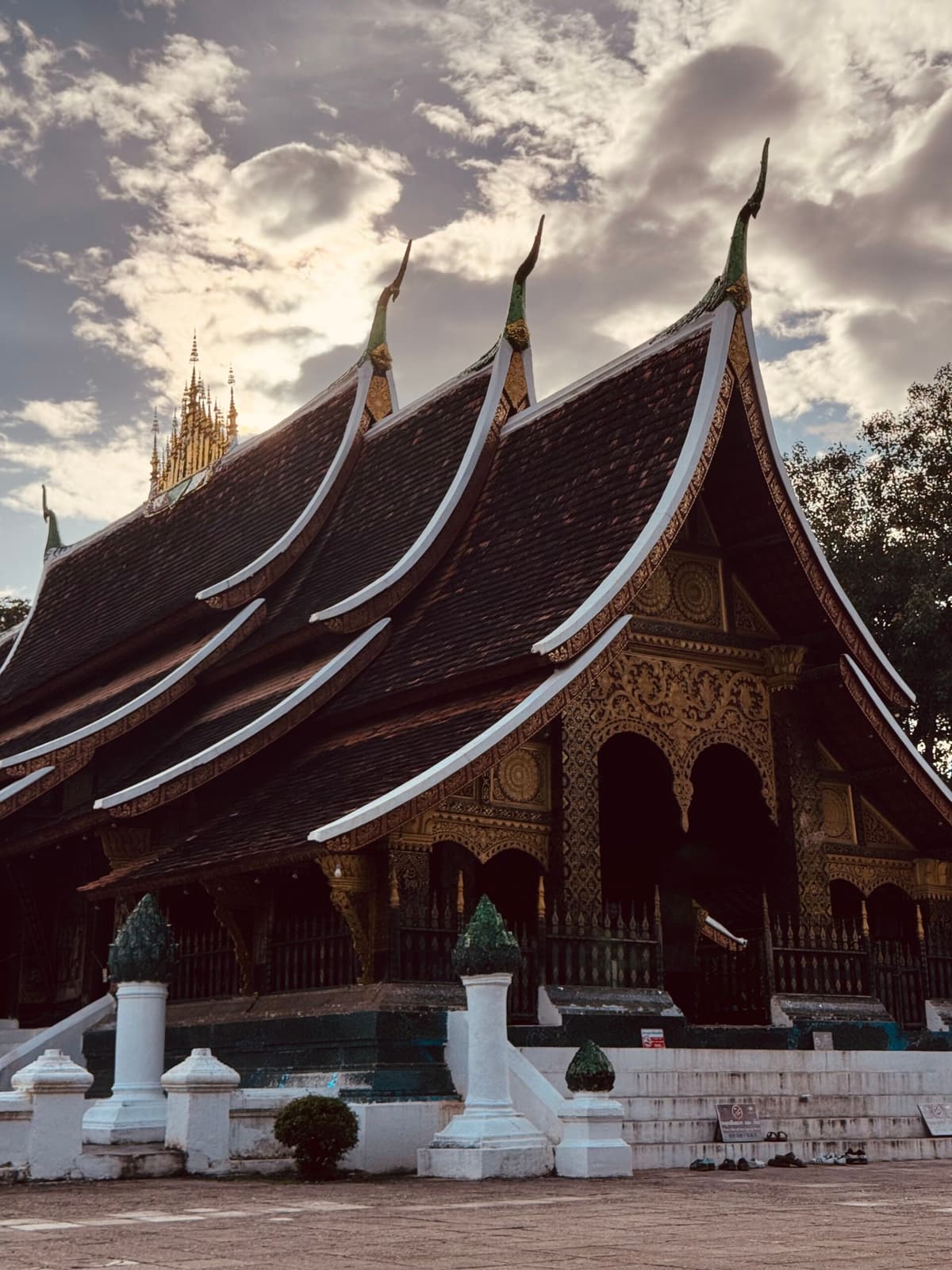 Los tejados bajos de largas curvas del Wat Xieng Thong, Luang Prabang